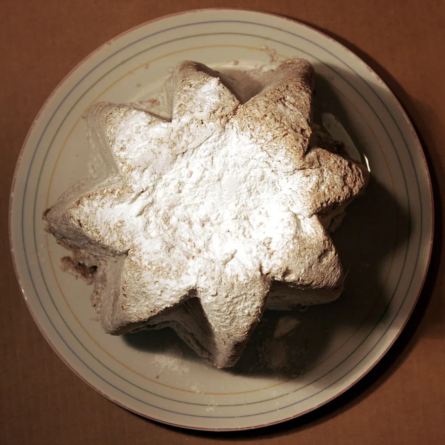Pandoro vu de dessus sur une assiette, avec sa forme d’étoile à huit branches saupoudrée de sucre glace