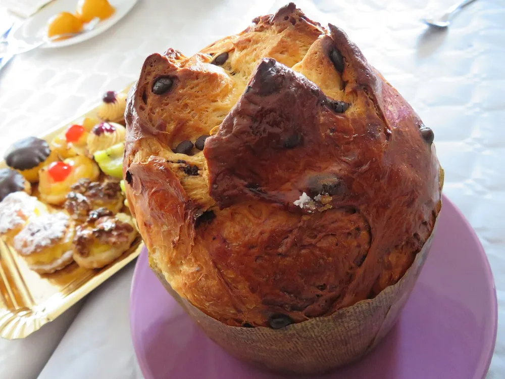 Panettone entier à la croûte dorée, dans son moule en papier, posé sur une table de fête
